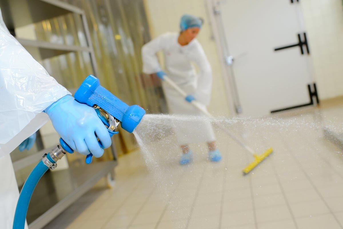 operatore che disinfetta l'interno di un laboratorio alimentare